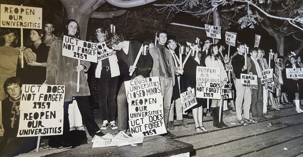 A group of people protesting in support of academic freedom. The posters say "Reopen our universities", "Closed universities, closed minds", and "UCT does not forget 1959".